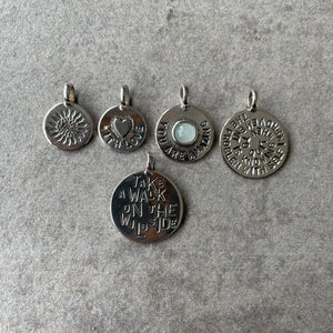 5 LifeStory disc charms with varied patterns and lettering. Left to right: Sunflower pattern; heart and  words WITH LOVE; pale blue stone and words YOU ARE AMAZING; large  disc with lettering THE PROBLEM WITH SELF IMPROVEMENT IS KNOWING WHEN TO STOP. Bottom charm, large with lettering TAKE A WALK ON THE WILDSIDE